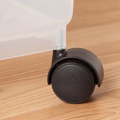 a close up of a plastic container on a wooden surface with a black handle and lid