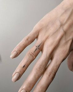 a person's hand with a small star tattoo on the middle finger and fingers