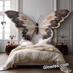 a bed with a butterfly shaped headboard and pillows on top of it in a white room