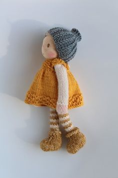 a knitted doll wearing a yellow dress and hat