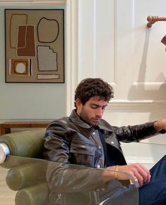 a man sitting in a chair with his foot on the glass table and looking down