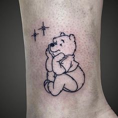 a small tattoo of a teddy bear holding a cross on the side of his leg