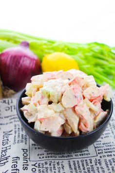 a black bowl filled with chicken salad next to asparagus