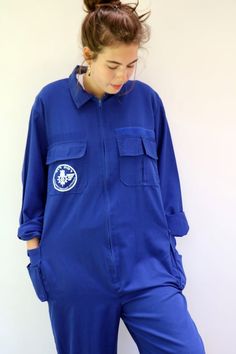 Vintage blue chore coveralls from Israeli flight school printed in Hebrew on the back and front..." Amal Ramat David Building the future"  with an F16 airplane drawing on the back panel, pockets with velcro opening, zips down the front, elastic waist on the back, soft cotton.  an oversize and loose fit can be worn by both men and women. aside from minor signs of wear...The back hem of the pants is worn, otherwise, good vintage condition clean ready to wear. **Model is 5'8" and a size s/m for ref Vintage Blue Long Sleeve Overalls, Retro Long Sleeve Overalls For Work, Retro Workwear Overalls, Blue Long Sleeve Utility Overalls, Long Sleeve Blue Cotton Overalls, Blue Utility Overalls For Streetwear, Blue Cotton Jumpsuits With Side Pockets, Blue Long Sleeve Relaxed Fit Overalls, Long Sleeve Overalls With Pockets For Streetwear