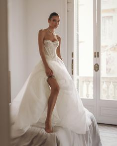 a woman in a wedding dress sitting on a bed