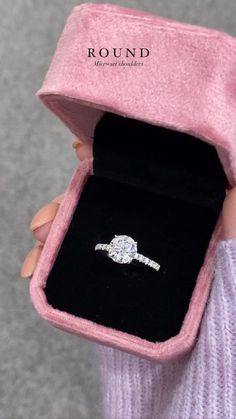 a person holding a ring in a pink box