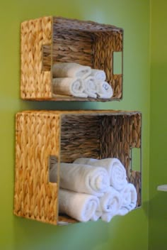 two baskets with towels hanging on the side of them in front of a green wall