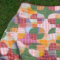 a patchwork quilt is laying on the grass