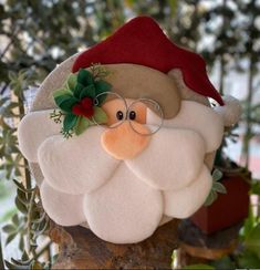 a stuffed santa clause with glasses and a red hat on top of a tree branch