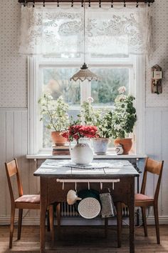 a table with flowers and potted plants on it in front of an open window