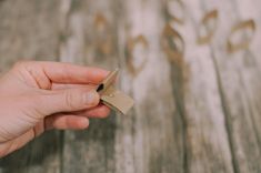 a person holding a piece of paper with a tag in their left hand on top of a wooden table