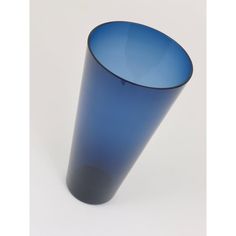 a blue glass vase sitting on top of a white table next to a black cup