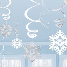 snowflakes and swirls hanging from the ceiling in a room with blue walls