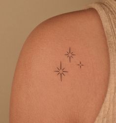 a woman's back shoulder with three small stars on the left side of her arm