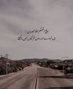 an empty road with the words written in arabic on it and mountains in the background