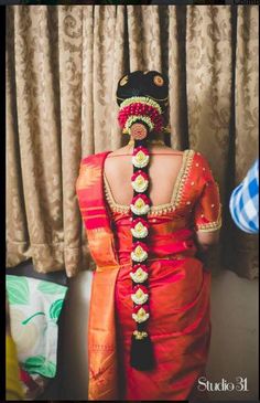 the back of a woman's head wearing an orange and red sari dress