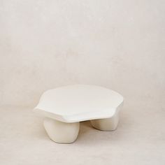 a white table sitting on top of a white floor next to a wall and chair