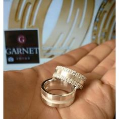 two gold wedding rings sitting on top of each other in front of a sign that says garnett