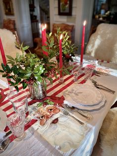 the table is set with red candles and place settings for two people to sit at