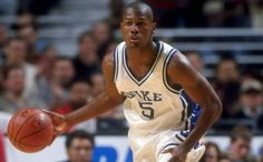 a male basketball player dribbling the ball during a game with an audience watching