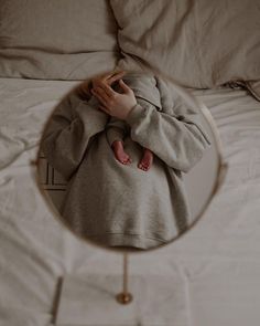 a person laying in bed with their feet on the pillow looking into a round mirror