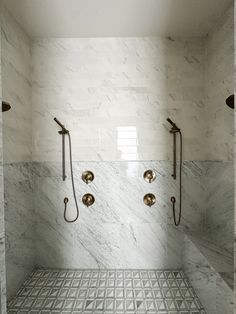 a bathroom with marble walls and floor, two shower heads on either side of the bathtub