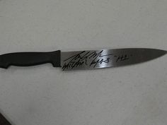 a knife that is sitting on top of a white counter with writing on the blade