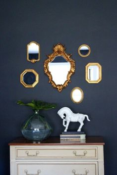 a white dresser topped with a vase filled with flowers next to a wall mounted mirror