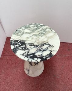 a white and black table sitting on top of a red floor next to a wall