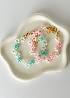 two bracelets are sitting on top of a white platter with beads and charms