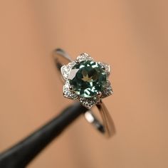 It is a lab green sapphire ring. The main stone is 7 mm*7 mm round cut).weight about 1.66 carats. The basic metal is sterling silver and plated with rhodium/14k white gold/14k rose gold/14k yellow gold You can also go to my shop Home for more elegant rings: https://www.etsy.com/shop/godjewelry?ref=hdr_shop_menu Customization is always welcome and please feel free to contact with me if you have any design ideas! Green Sapphire Rings With Halo Setting, Green Sapphire Ring With Halo Setting For Promise, Green Sapphire Solitaire Diamond Ring, Green Sapphire Jewelry With Center Stone, Green Sapphire Jewelry With Halo Setting, Green Sterling Silver Round Diamond Ring, Green Sterling Silver Diamond Ring, Elegant Green Sapphire Ring With Halo Setting, Elegant Green Sapphire Ring With Center Stone