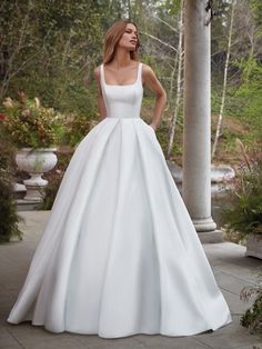 a woman in a white wedding dress posing for the camera with her hands on her hips