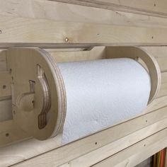 a toilet paper dispenser mounted to the side of a wooden wall in a bathroom