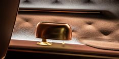 a gold lamp sitting on top of a table next to a chair and window sill