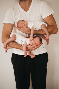 a man holding two babies in his arms