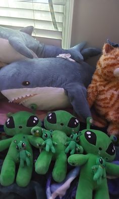 several stuffed animals sitting on top of a bed next to a cat and other stuffed animals