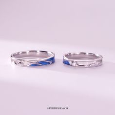 two silver rings with blue enamel bands on them, one has a diamond in the middle