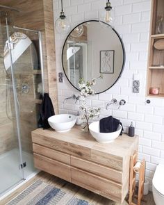 a bathroom with two sinks and a large round mirror on the wall next to a walk in shower