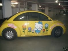 a yellow car with hello kitty painted on it's side in a parking garage