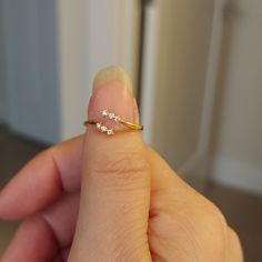 a woman's hand holding a tiny gold ring with three small diamonds on it