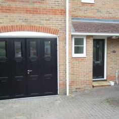 two black doors in front of a brick house