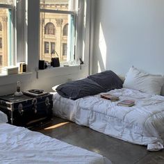 two beds in a room with white sheets and pillows on the floor next to each other