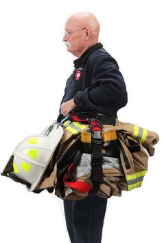 an older man carrying fireman's gear on his back and looking off to the side