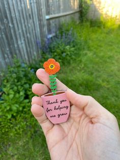 a hand holding a flower pot with a note attached to it that says thank you for helping me grow