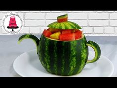 a watermelon teapot with slices of fruit in it on a white plate