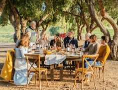 a group of people sitting around a table with food and drinks in front of them