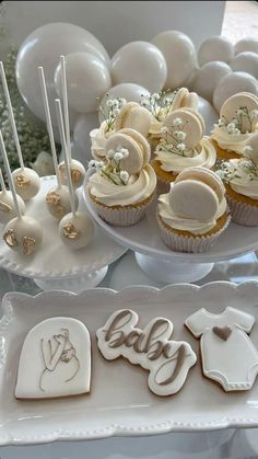 cupcakes and cookies on plates with balloons in the background