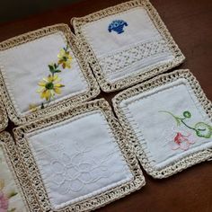 four embroidered coasters on a table with white crocheted edges and floral designs