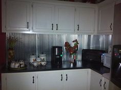 a kitchen with white cupboards and black counter tops in front of a microwave oven