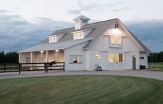 a large white barn sitting on top of a lush green field